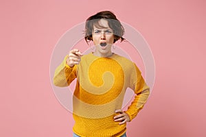 Shocked angry young brunette woman girl in yellow sweater posing isolated on pastel pink background, studio portrait