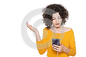 Shocked angry young girl looking at her mobile phone in disbelief. Teenager staring at shocking text message on her phone.