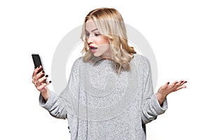 Shocked angry young woman looking at her mobile phone in disbelief. Woman staring at shocking text message on her phone.