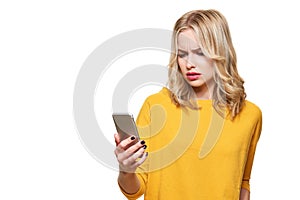 Shocked angry young woman looking at her mobile phone in disbelief. Woman staring at shocking text message on her phone. photo