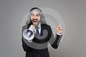 Shocked arabian muslim businessman in keffiyeh kafiya ring igal agal black suit shirt tie isolated on gray background