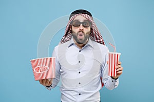 Shocked arabian muslim man in keffiyeh kafiya ring igal agal 3d imax glasses isolated on pastel blue background. People