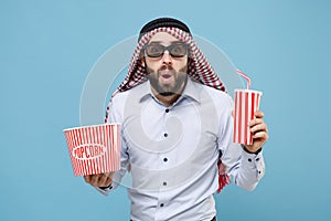 Shocked arabian muslim man in keffiyeh kafiya ring igal agal 3d imax glasses isolated on pastel blue background. People