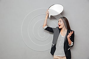 Shocked asian business woman holding blank speech bubble overhead