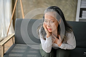 Shocked Asian mature woman look in the distance, thinking and worried about something