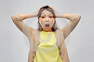 Shocked asian woman holding to her head