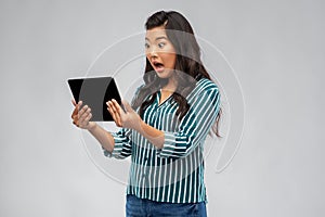 Shocked asian woman using tablet computer