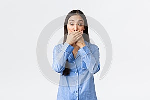 Shocked astounded asian girl in blue pajamas, gasping and stare shook camera, being speechless with awful news, witness