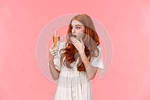 Shocked and astounded redhead woman surprised as cant remember when she took glass with champagne, have drinking