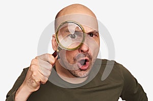 Shocked bald guy looking through magnifying glass