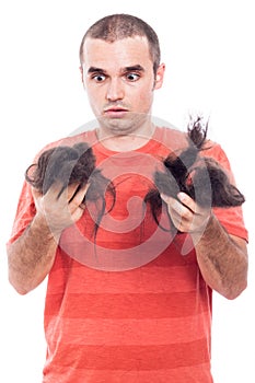 Shocked bald man holding his shaved hair