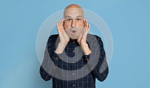 Shocked bald man isolated over blue