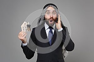Shocked bearded arabian muslim businessman in keffiyeh kafiya ring igal agal classic black suit tie  on gray photo