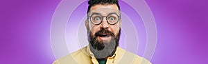 Shocked bearded man in eyeglasses looking at camera, isolated