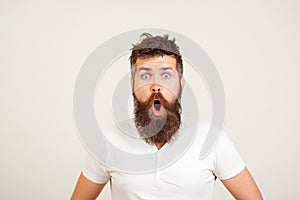 Shocked bearded man stares at camera. Bearded hipster guy widely opened mouth and eyes. Human face expressions and emotions. Wow!