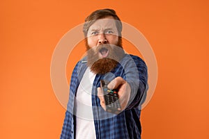 Shocked Bearded Man Watching Television Pointing Remote Controller In Studio