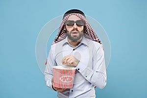 Shocked bearded young arabian muslim man in keffiyeh kafiya ring igal agal 3d imax glasses isolated on pastel blue