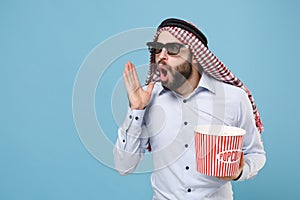 Shocked bearded young arabian muslim man in keffiyeh kafiya ring igal agal 3d imax glasses isolated on pastel blue