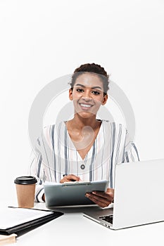 Shocked beautiful african woman posing isolated over white wall background using laptop computer holding clipboard