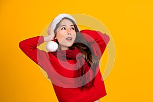 Shocked beautiful Asian girl wearing christmas hat isolated on yellow background. She covered both ears with her hands