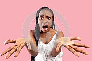 Shocked black woman looking at camera with open mouth, gesturing WTF on pink studio background