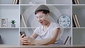 Shocked boy of 13 years old reading terrible news while using smartphone at home. Surprised teenager surfing the