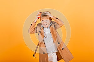 Shocked boy holding clock alarm, copy space. Kid isolated over yellow background. Time for school