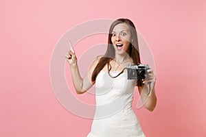 Shocked bride woman in wedding dress pointing index finger holding retro vintage photo camera choosing staff