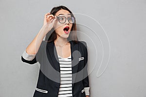 Shocked business woman in eyeglasses looking away with open mouth