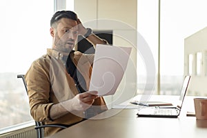 Shocked Businessman Holding Paper Having Problem With Taxes In Office