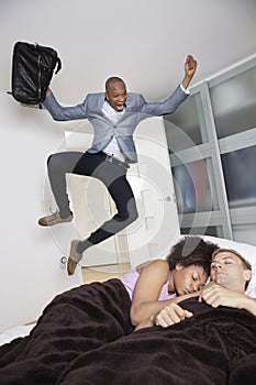 Shocked businessman looking at couple sleeping in bed