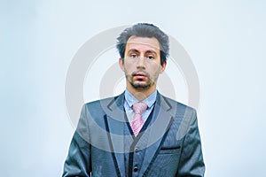 Shocked businessman with tousled hair looks into the camera.