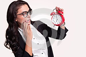 Shocked businesswoman looking at alarm clock