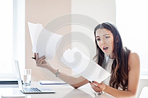 Shocked businesswoman reading paper at workplace in office