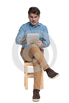 Shocked casual man reading and writing on his tablet