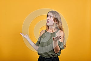 Shocked cheerful young woman in haki shirt, looking camera, spreading hands