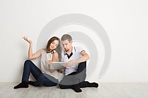 Shocked couple using laptop, sitting on floor