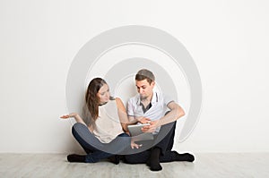 Shocked couple using laptop, sitting on floor