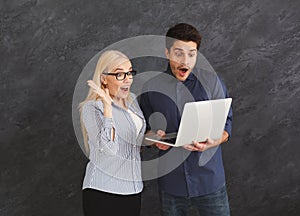 Shocked couple using laptop at studio