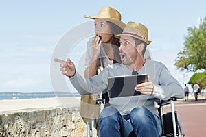 shocked couple in wheelchair strolling by sea