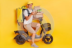 Shocked courier on electric scooter with thermo backpack delivering pizza and coffee to go, holding cell phone, looking at screen