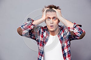 Shocked dazed young man holding head with both hands