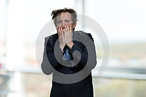 Shocked desperate businessman covering his face.