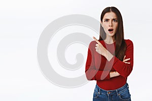 Shocked dissatisfied pretty, feminine brunette girl in red sweater looking concerned and disappointed, gasping open