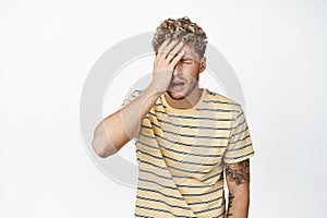 Shocked distressed blond man making facepalm, standing frustrated and upset, crying and sobbing, standing in casual