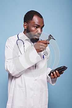 Shocked doctor inspecting an otoscope