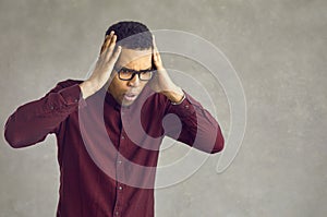 Shocked emotional african american man looking down toughing head studio shot