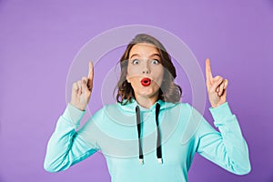 Shocked emotional young woman posing isolated over purple background wall