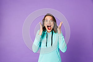 Shocked emotional young woman posing isolated over purple background wall