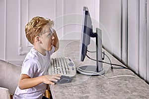 Shocked european boy 6 years old looks at screen of computer.